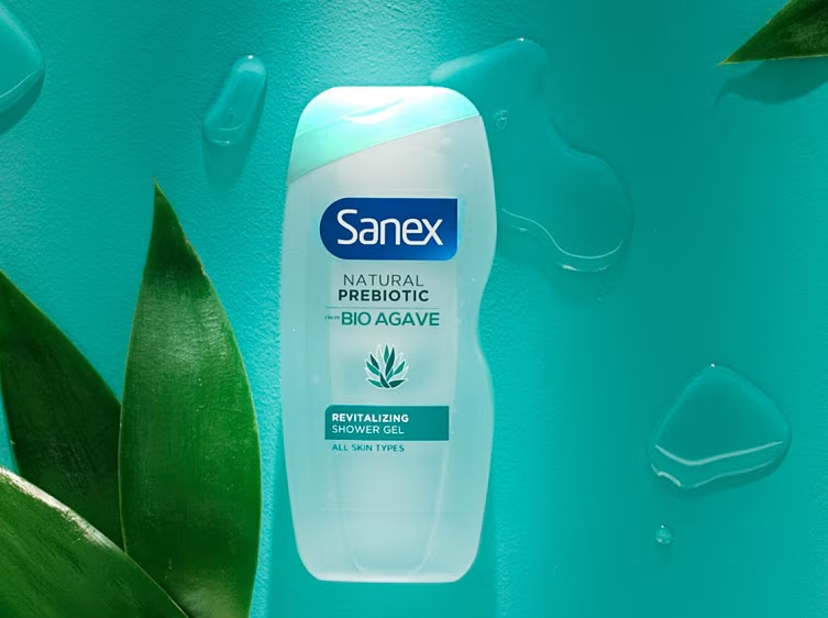 Sanex Natural Prebiotic Bio Agave Hydraterende Douchegel met groen label op een turquoise achtergrond met groene bladeren.